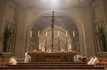 Leveät askelmat basilikan alttarille. Basilika on korkea ja siellä on risti ja isoja kynttilöitä.