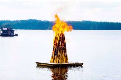 Meressä lautalla koivuista koottu kokko jossa tuli.